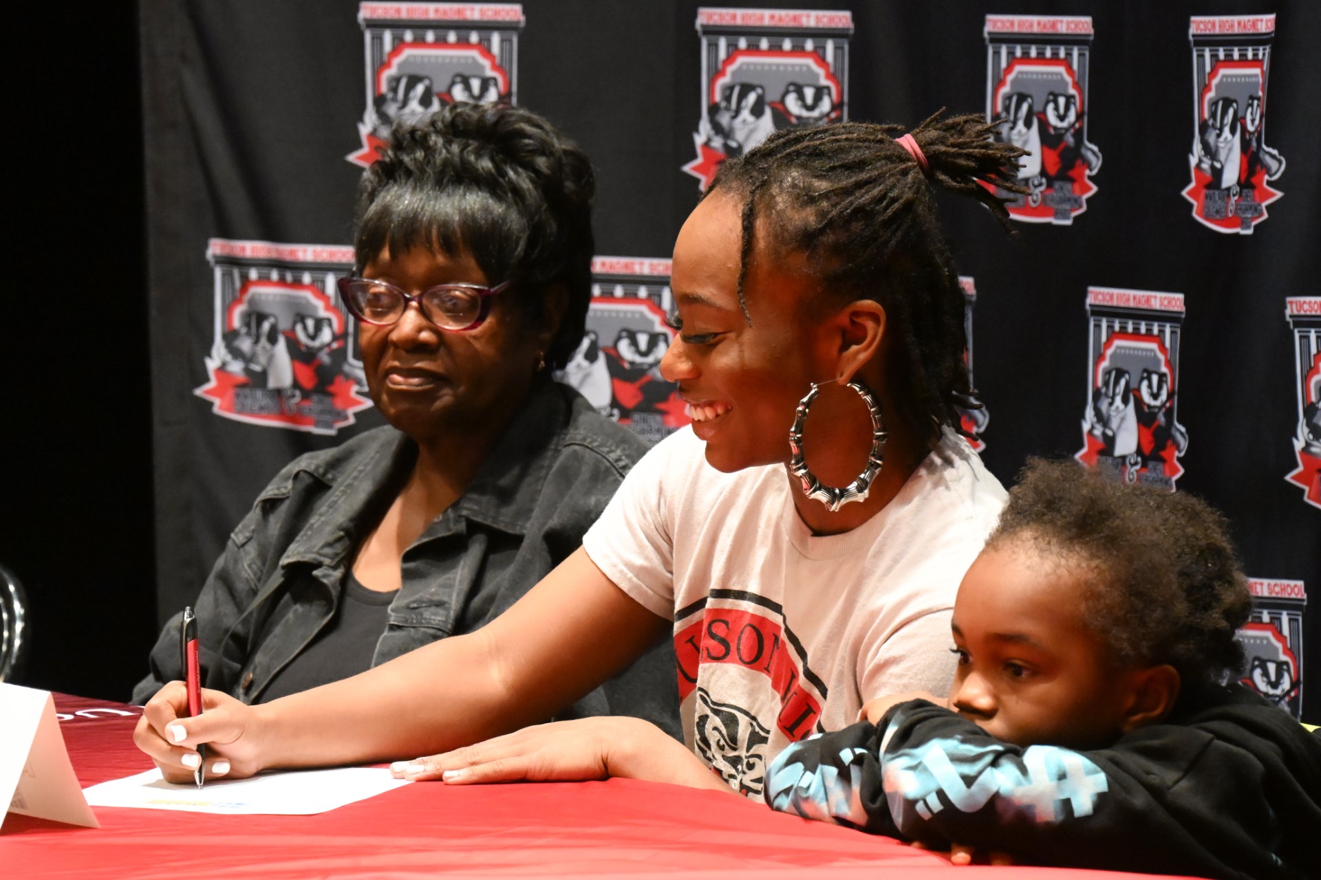 Lahtahjah Cooper signs her letter of intent with her family next to her